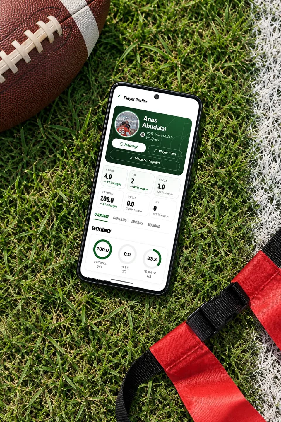 GameGrid player profile on an Android phone on a grass field beside a football