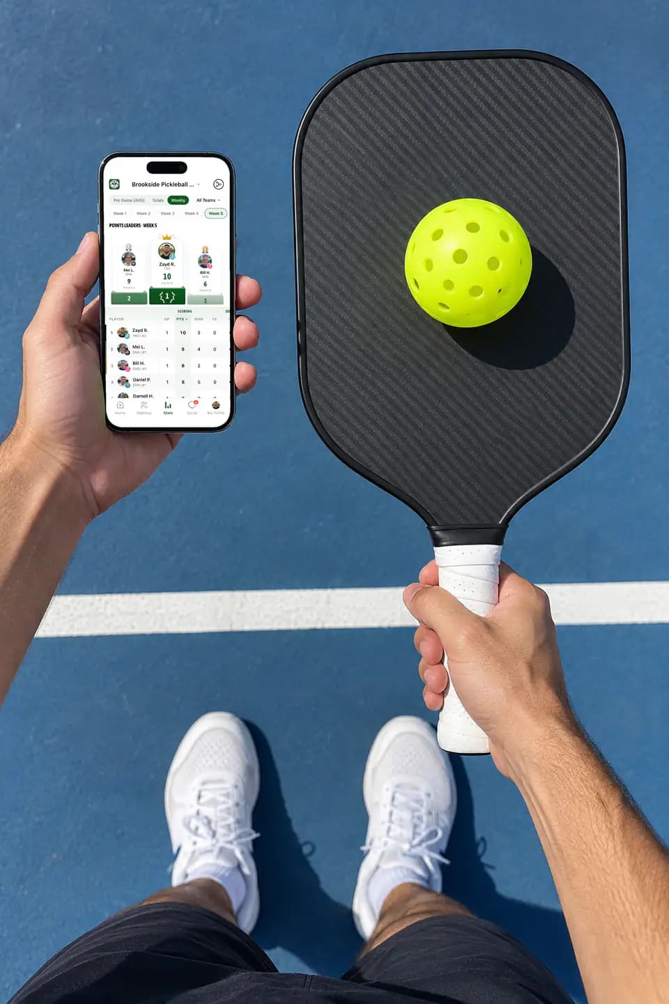 Player holding an iPhone with GameGrid pickleball leaders over a blue court